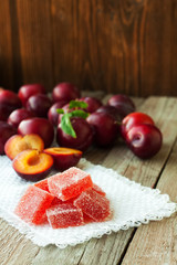 Homemade plum jelly and plums on wood table