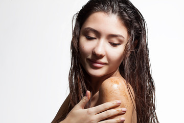 Brunette woman cleans the skin of the body coffee scrub on a white background isolated