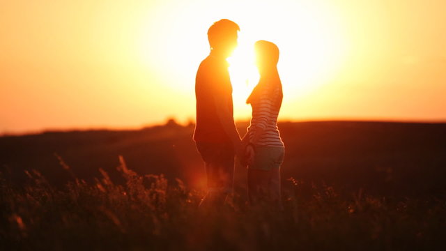 lovers in field at sunset cuddling