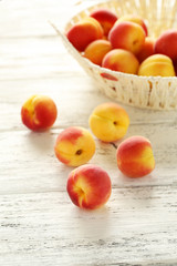 Fototapeta na wymiar Fresh apricots in basket on a white wooden background