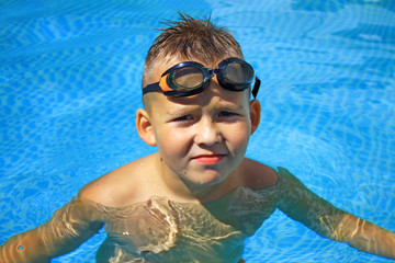 A little boy standing in a pool with a swimming mask and snorkel