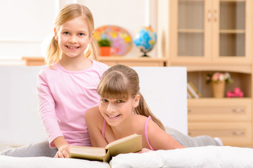 Cheerful sisters reading book 