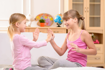 Positive little sisters clapping their hands 
