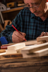 Senior carpenter marking a measurement on a wooden plank
