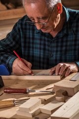 Senior carpenter marking a measurement on a wooden plank