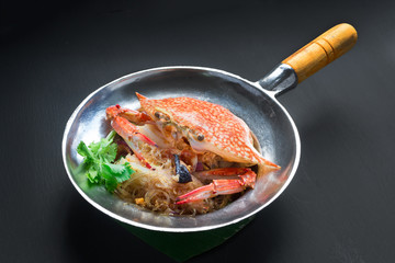 Casseroled crab with glass noodles on black background