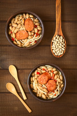 Traditional Chilean dish called Porotos con Riendas (English: beans with reins), made of cooked beans, linguine (flat spaghetti) and served with fried sausage, photographed on wood with natural light