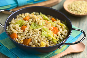 Vegan stew made of wheat grains, savoy cabbage, carrot, pumpkin and onion, photographed with natural light (Selective Focus, Focus one third into the dish)