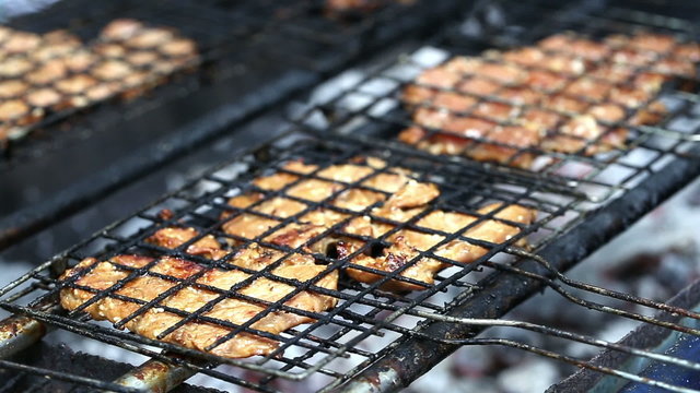 pork chops getting grilled on grill with flames.
