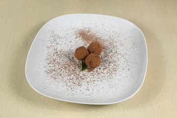three truffle sprinkled with cocoa on a white plate