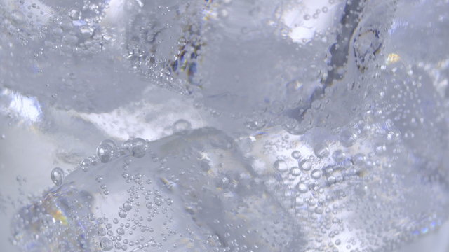 Pouring soda water with ice and bubbles in the glass. Сlose-up 4K UHD 2160p footage.
