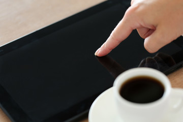 Female hand pointing in black tablet pc and using it closeup