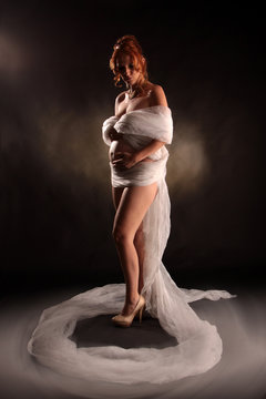 Eine nackte schwangere Frau in ein Tuch gewickelt