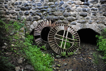 Old metal waterwheels near the ancient building of mill 