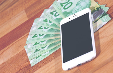 An image of a pile of cash under a mobile phone. It describes the situation nowadays, people are making money on the internet.