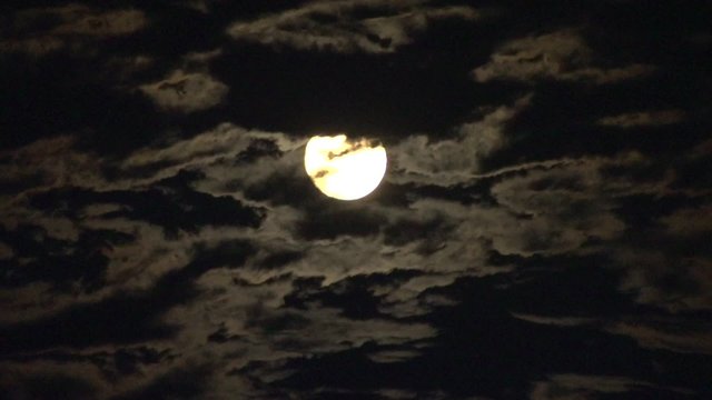 Full moon in the sky hides behind clouds. Time lapse. 