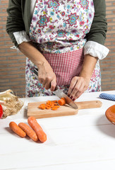 Woman cutting vegetables on wooden board