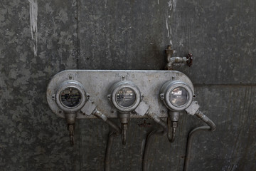 A set of gauges on a wall in an industry warehouse 
