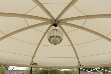 A mosaic ball in a tent with some trees in the background 