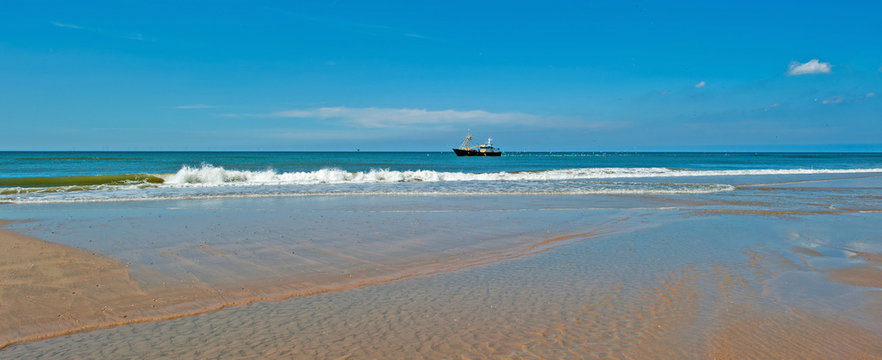 Trawler fishing at sea below a cloudy sky 