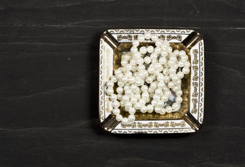 Pearl necklace on a black wooden surface