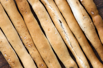 Salted Italian grissini on wooden cutting board close up