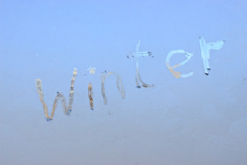 "winter" written on frosty winter window background.
