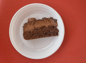 Piece of a chocolate cake in a disposable plate