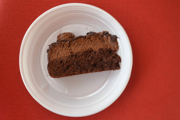 Piece of a chocolate cake in a disposable plate