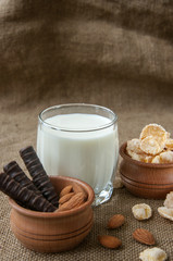 A glass of milk with almond nuts, corn flakes, chocolates,  on s