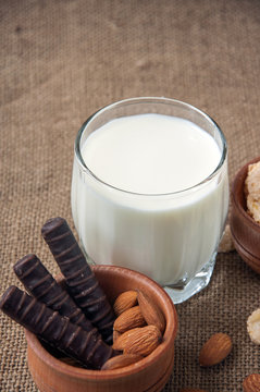 A glass of milk with almond nuts, corn flakes, chocolates,  on s