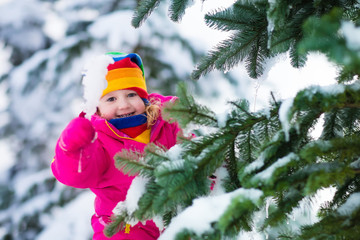 Little girl with icicle in snowy winter park