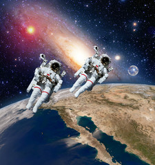 Two astronauts spaceman planet earth outer space moon milky way galaxy. Elements of this image furnished by NASA.