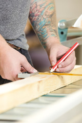 Obraz premium Carpenter measures the length of a wood plank before sawing
