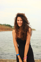 Fototapeta na wymiar Beautiful slim brunette girl model posing in fashion dress by the sea, outdoor portrait