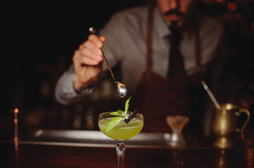 Close-up of bartender making green cocktail