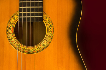 Old guitar close up isolated on a burgundy background