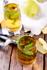 Glasses of apple juice with fruits and fresh mint on table close up