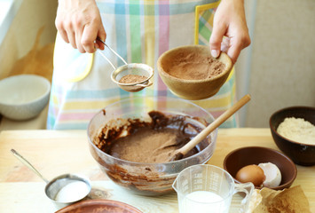 Woman preparing dough for chocolate pie on table close up