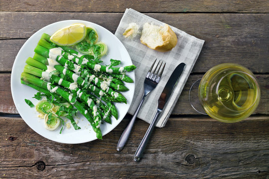 Fototapeta Served wooden table with asparagus dish and wine, close up