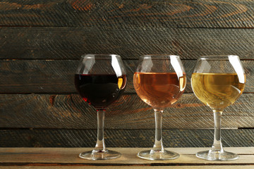 Glasses with white, rose and red wine on wooden background