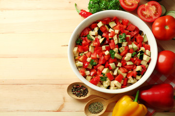 Ratatouille before cooking and ingredients, on wooden background