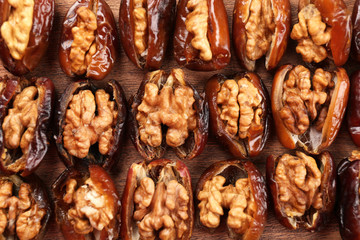 Walnut in date fruit on wooden table, close-up