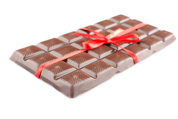 Milk chocolate bar with red bow on color wooden background
