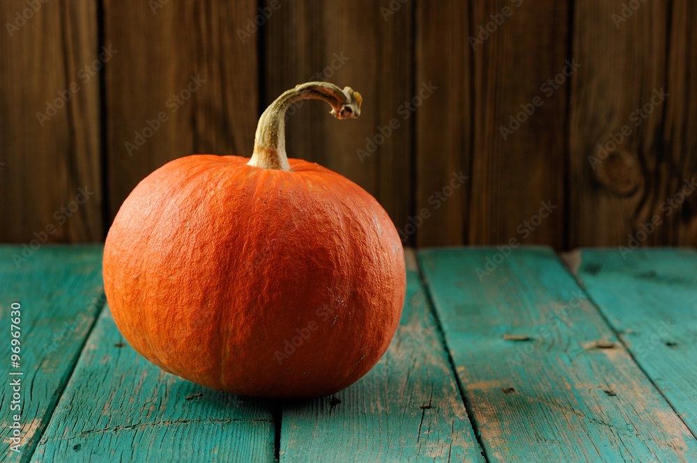 Wall mural whole orange pumpkin on turquoise wooden table copyspace