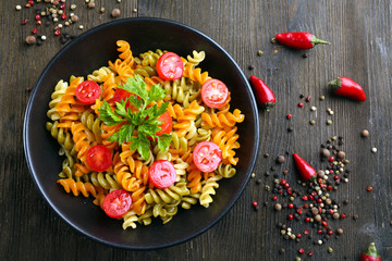 Delicious macaroni dish in black bowl on decorated with pepper wooden table