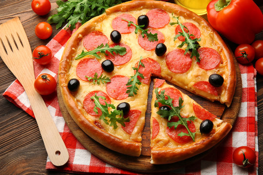 Delicious tasty pizza with salami and olives on wooden background, close up