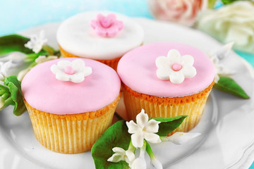 Tasty cupcakes on plate, on color wooden background