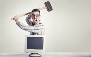 young angry nerd destroying old computer monitor