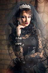 Portrait of beautiful young brunette girl in black dress and veil in the Gothic style
